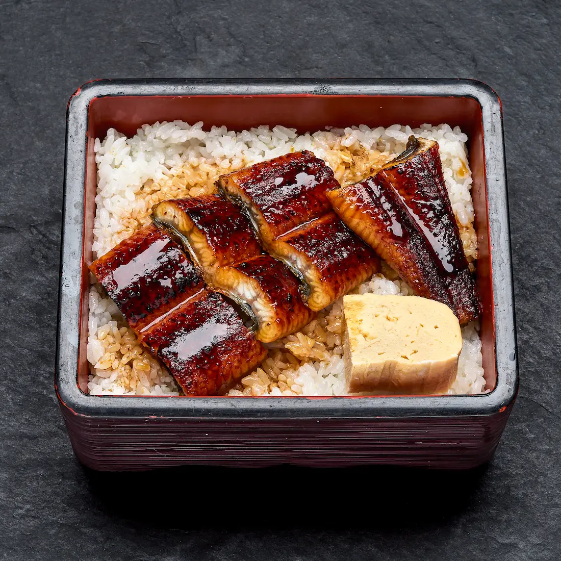 Una Juu — gegrillter Aal in Unagi-Sauce auf Reis, serviert in schwarzer Lackbox