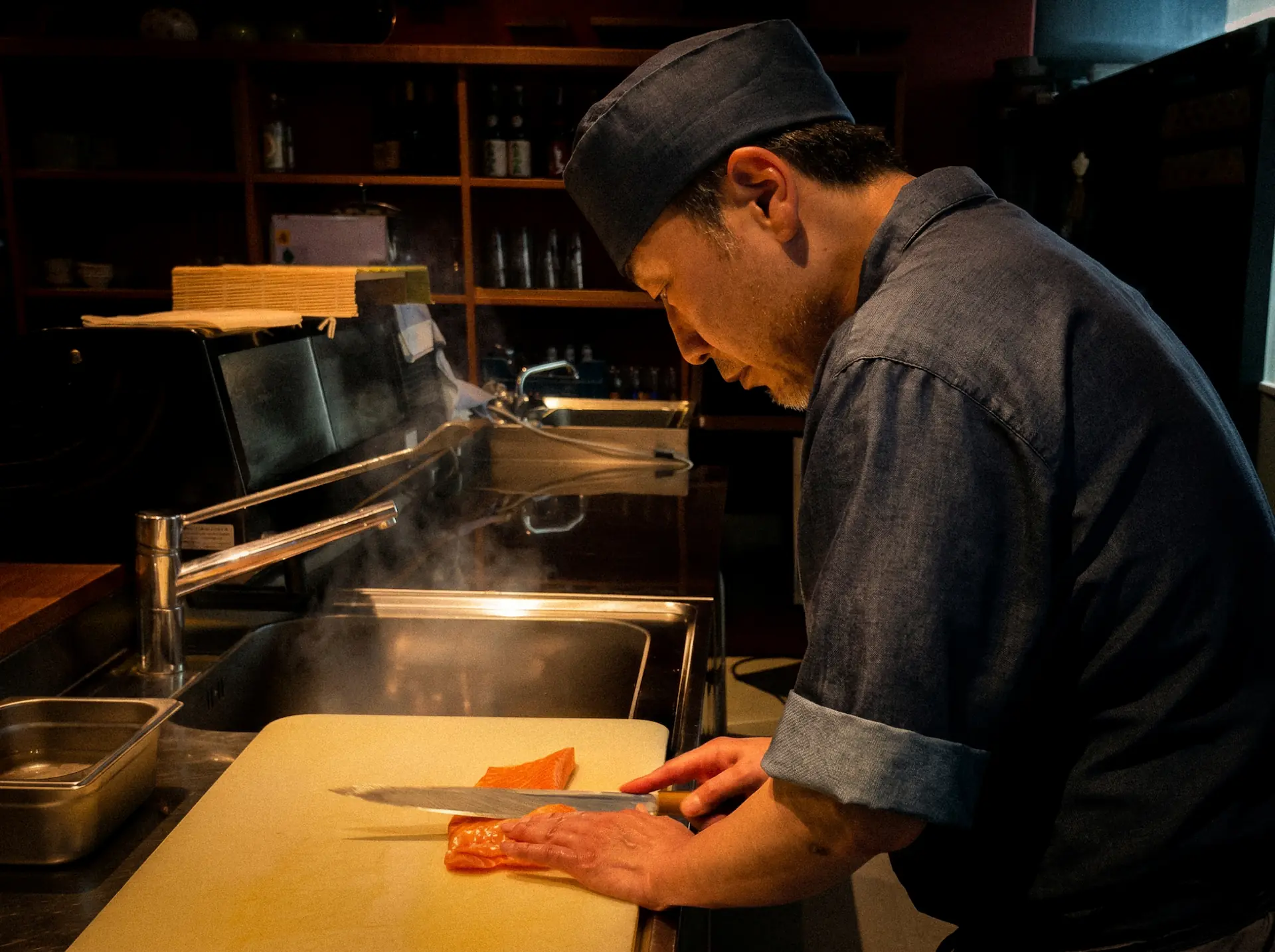 Küchenchef von Iroha schneidet frischen Lachs für Sashimi